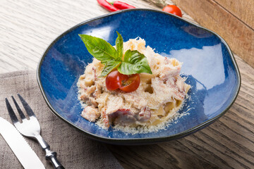 Pasta carbonara served in a creamic bowl with fresh basil
