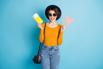 Photo of impressed brunette lady hold plane ticket wear cap spectacles bag shirt isolated in vivid...