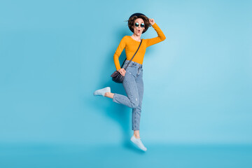 Full size profile photo of optimistic brunette short hairdo lady jump with bag wear shirt jeans sneakers isolated on blue color background