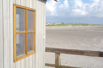 close up of window from cottage by a sandy beach