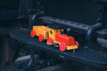  small wooden toy train on steps of an historic big train