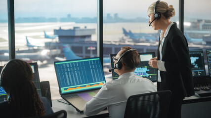 Female and Male Air Traffic Controllers with Headsets Talk in Airport Tower. Office Room is Full of Desktop Computer Displays with Navigation Screens, Airplane Flight Radar Data for the Team. © Gorodenkoff