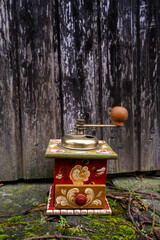 old painted coffee grinder outsdie in front of weathered wooden door