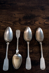 four spoons lie on table while one lies the other way around