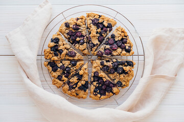Freshly baked oat blueberry scones on cooling rack on white wooden background. Sweet food with natural ingredients. Vegan gluten free pastry..