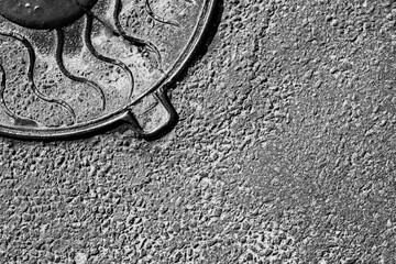 Old and cracked manhole cover in asphalt. View from above