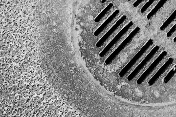 Old manhole cover with holes in asphalt. View from above