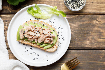 Avocado, canned tuna toast on wooden table background. Healthy food, avocado open sandwich for breakfast or lunch. Flat lay, top view, copy space