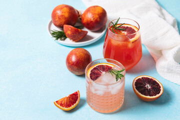 Blood orange cocktails with fresh fruits on blue table background. Summer cocktails, lemonade, refreshing drinks, low alcohol mocktail, party concept. Copy space