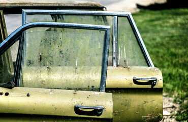 Puertas abiertas de un auto viejo color verde abandonado por muchos años al costado del camino