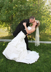 young groom dipping modern bride outdoors full-length