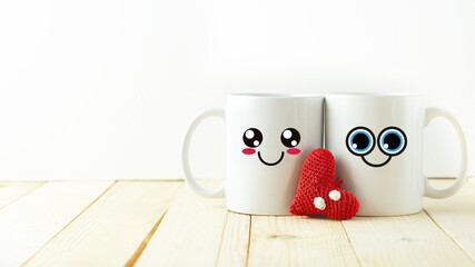 Two mugs with smiley faces drawn with a heart in the center. International Friendship Day