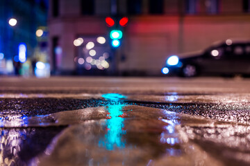 Nights lights of the big city, the night avenue with a car standing at the traffic lights. Close up...