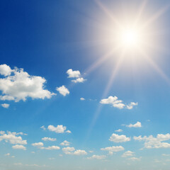 blue sky with cumulus clouds and summer or spring sun as nature background.