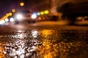 Nights lights of the big city, the night avenue with driving cars. Close up view from the level of asphalt