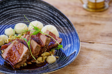 Tataki de ternera con verduras y pure de patata servidos en un plato de cerámica