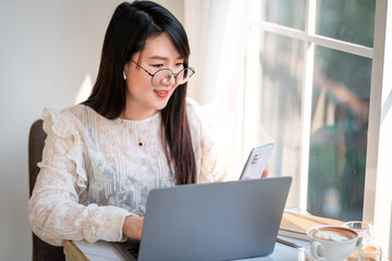 Happy of asian freelance people Businesswoman writing message on smartphone and hold a coffee cup mug casual working with laptop computer at the cafe,Business Lifestyle