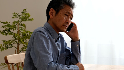 通話をしながら困り果てるシニア男性