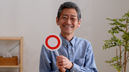 笑顔でまるのプレートを持つシニア男性