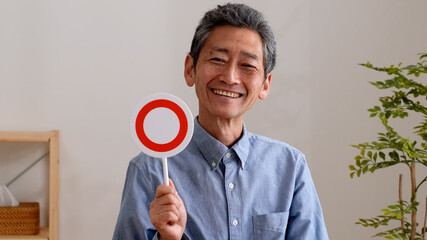 笑顔でまるのプレートを持つシニア男性