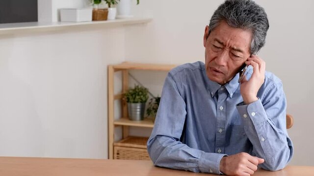 通話をしながら困り果てるシニア男性