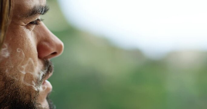 Close-up of a man with a beard and long brown hair. He is smoking a cigarette, there is smoke coming from his mouth  - Red Camera 4K