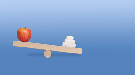 scales with red apple and white sugar on the blue background with copy space
