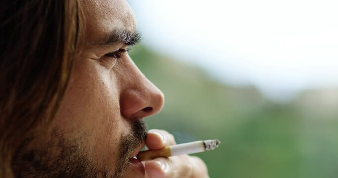 Man smoking a cigarette, there is smoke coming from his mouth. He has a beard and long brown hair.  - Red Camera 4K