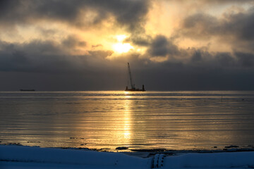 Beautiful sunset in Arctic sea. Barge with crane. Golden hour. Construction Marine offshore works. Dam building, crane, barge, dredger.