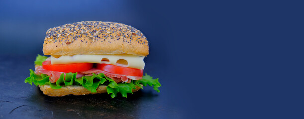 close-up of appetizing sandwich with ripe tomato slices, green lettuce, cheese, ham, ruddy poppy seed bun, quick snack concept, making of fastfood at home, chef is cooking sandwich, fast food, diet