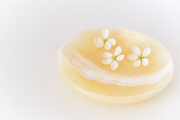 Three beautiful white flowers of apple tree on an onyx plate.
