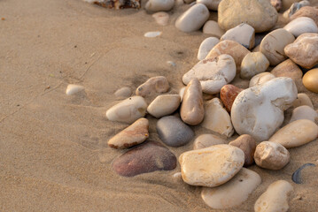 Fototapeta na wymiar Some rocks on the Mediterranean beach. Close up with sand and smooth rounded rocks 