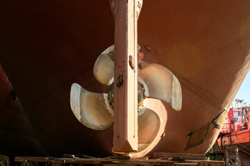 Variable pitch propeller and rudder. Cargo vessel ashore on ship repairing yard.