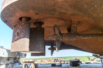Fixed blade propeller and rudder with shells. Cargo vessel ashore on ship repairing yard.