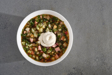 plate of cold okroshka soup with kvass on a gray concrete background. Top view with space for text - obrazy, fototapety, plakaty