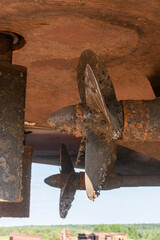 Fixed blade propeller and rudder with shells. Cargo vessel ashore on ship repairing yard.