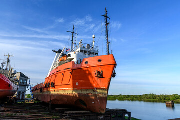Tug vessel ashore on ship repairing yard. Summer time.