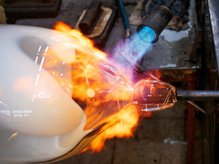 Master glassmaker heats a fire torch glass ball on a glass pipe. - obrazy, fototapety, plakaty