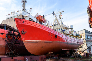 Small vessel ashore on ship repairing yard. Summer time.