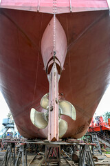 Variable pitch propeller and rudder. Cargo vessel ashore on ship repairing yard.