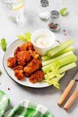 Buffalo style barbecue cauliflower  with fresh celery sticks  and sauce . Light gray stone background.