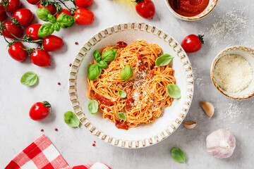 Tasty appetizing classic italian spaghetti pasta with tomato sauce,  parmesan cheese and fresh basil leaves.  Light gray stone background, top view