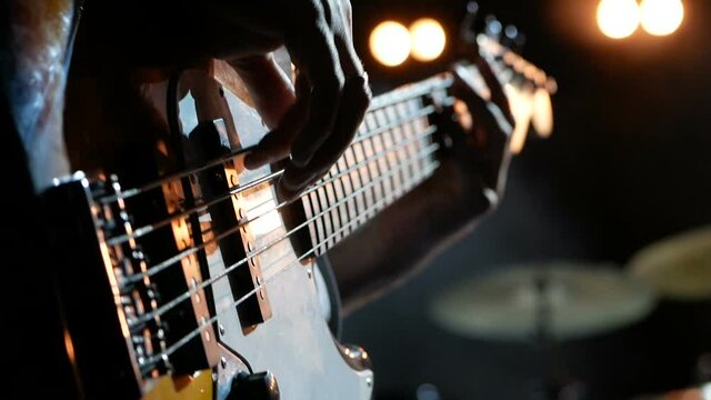 Musician playing bass guitar, close up view.