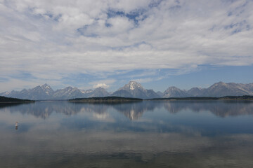 Scenic view of a lake with mountains in the background and lake reflections in Grand Teton National Park on a cloudy day