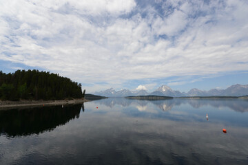 Scenic view of a lake with mountains in the background and lake reflections in Grand Teton National Park on a cloudy day