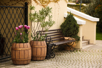 House exterior decorated with flower pots made of old wooden barrels.