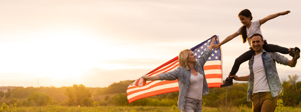 Family Holding Up An American Flag In A Field.