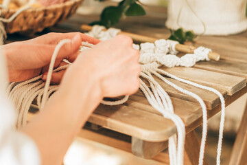 Close up of women's hands weaving macrame in a home workshop.Home decor.Handmade concept.Selective focus with shallow depth of field.