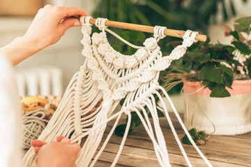 Close up of women's hands weaving macrame in a home workshop.Home decor.Handmade concept.Selective...