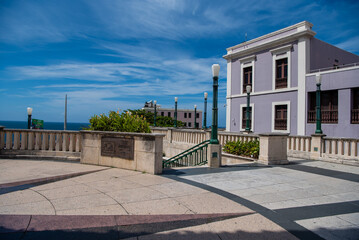 Fototapeta na wymiar A modern lavender colored home sits next to pretty architectural site in San Juan, Puerto Rico.